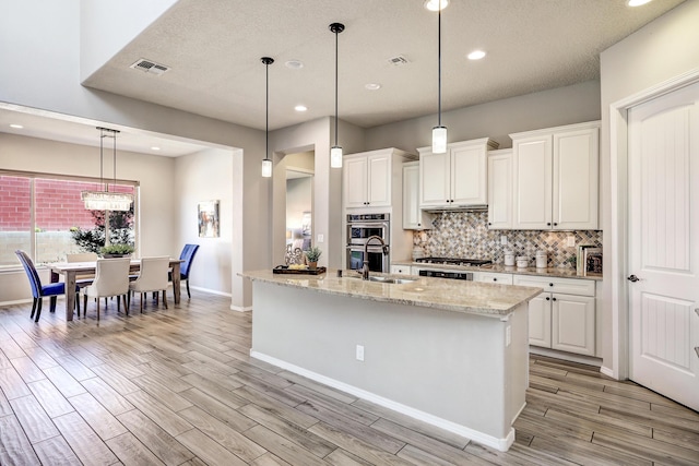 843 Mesa Roja Trl NE, Rio Rancho, NM 87124 - kitchen featuring a sink, light wood-type flooring, backsplash, white cabinets, and baseboards