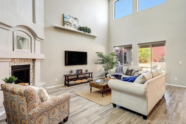 843 Mesa Roja Trl NE, Rio Rancho, NM 87124 - living area with a towering ceiling, light wood-type flooring, a fireplace with raised hearth, healthy amount of natural light, and baseboards