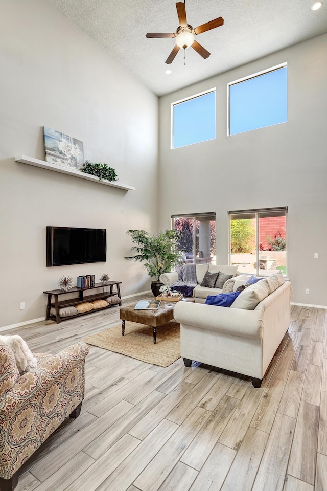 843 Mesa Roja Trl NE, Rio Rancho, NM 87124 - living area featuring a high ceiling, light wood-type flooring, ceiling fan, plenty of natural light, and a textured ceiling
