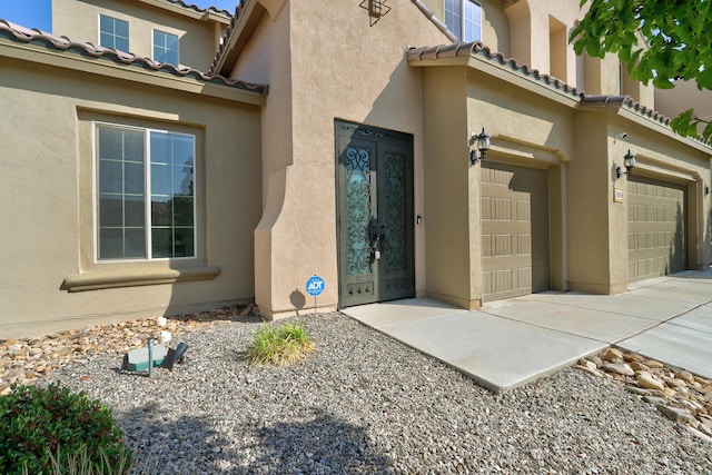 843 Mesa Roja Trl NE, Rio Rancho, NM 87124 - view of exterior entry with stucco siding, a tiled roof, and an attached garage