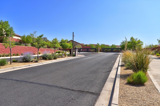 843 Mesa Roja Trl NE, Rio Rancho, NM 87124 - view of asphalt road with a gate, curbs, and a gated entry