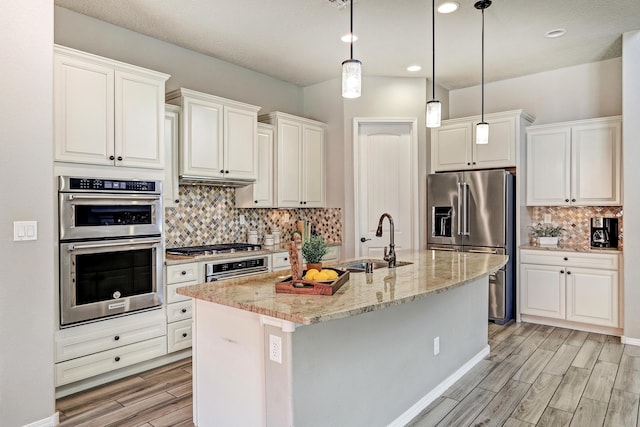 843 Mesa Roja Trl NE, Rio Rancho, NM 87124 - kitchen featuring stainless steel appliances, light wood-type flooring, tasteful backsplash, a sink, and white cabinetry