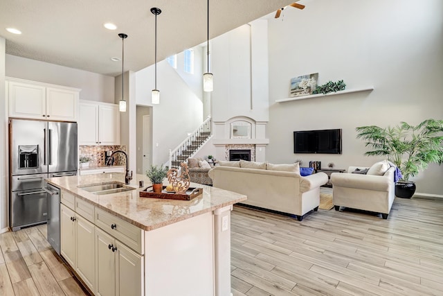 843 Mesa Roja Trl NE, Rio Rancho, NM 87124 - kitchen featuring appliances with stainless steel finishes, a sink, light wood-style floors, light stone countertops, and a towering ceiling