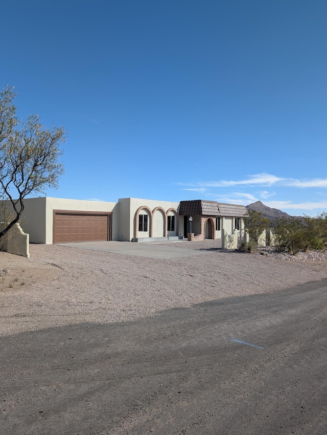 301 Stagecoach Dr, Elephant Butte, NM 87935 - view of front facade with stucco siding, driveway, a garage, and a mountain view