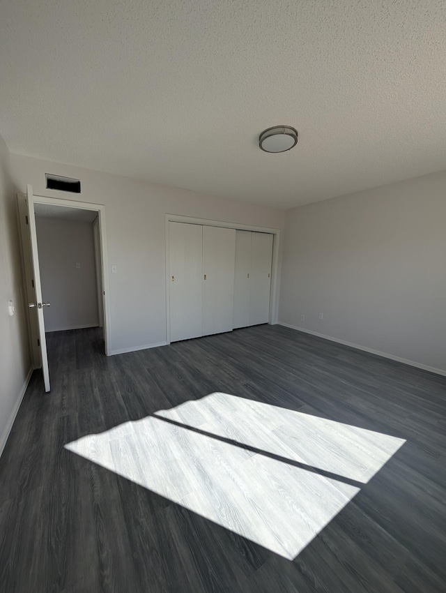 301 Stagecoach Dr, Elephant Butte, NM 87935 - unfurnished bedroom featuring dark wood-style flooring, baseboards, a textured ceiling, and a closet