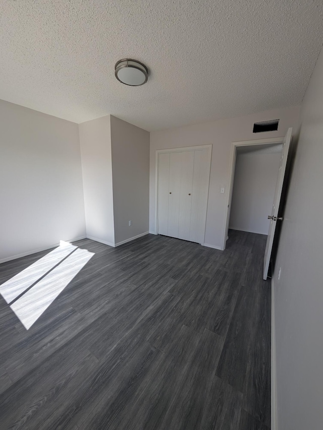 301 Stagecoach Dr, Elephant Butte, NM 87935 - unfurnished bedroom featuring dark wood finished floors, a textured ceiling, a closet, and baseboards