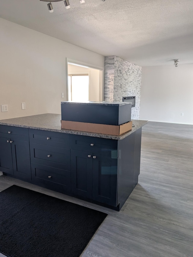 301 Stagecoach Dr, Elephant Butte, NM 87935 - kitchen with wood finished floors, a peninsula, a textured ceiling, open floor plan, and a fireplace