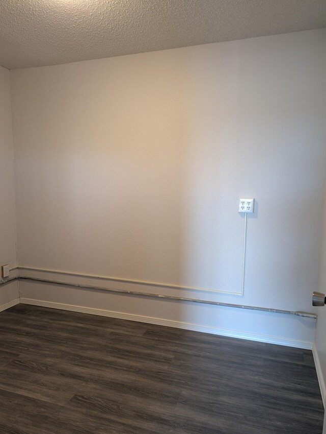301 Stagecoach Dr, Elephant Butte, NM 87935 - empty room with dark wood-type flooring, baseboards, and a baseboard heating unit
