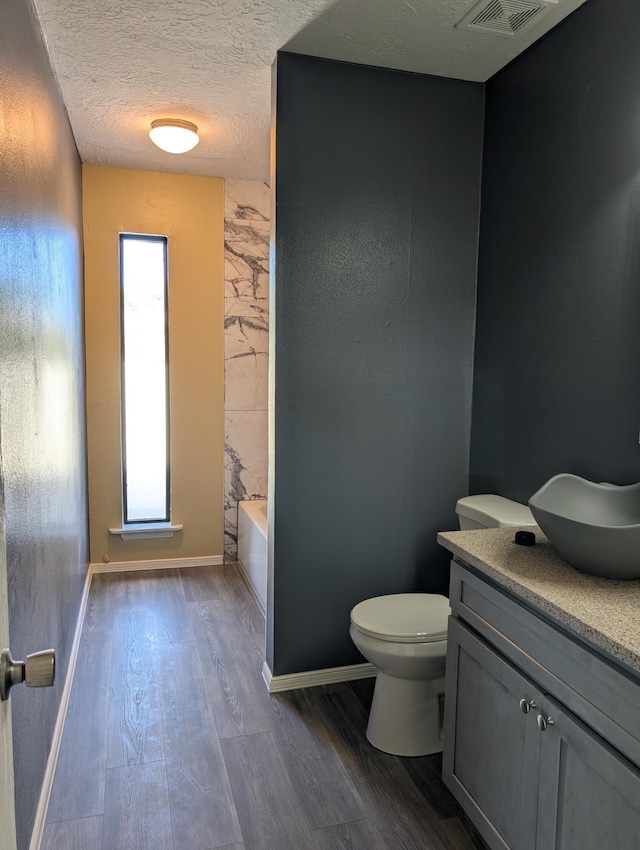 301 Stagecoach Dr, Elephant Butte, NM 87935 - full bath with wood finished floors, vanity, toilet, a bath, and a textured ceiling