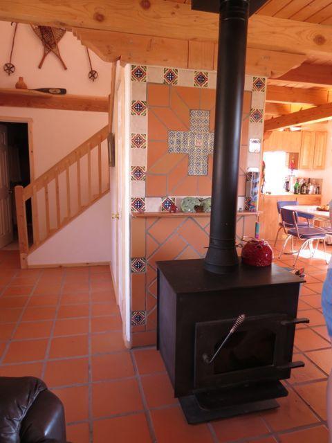 403 Candy Kitchen Rd, Ramah, NM 87321 - living area featuring a wood stove, stairs, beam ceiling, and light tile patterned flooring