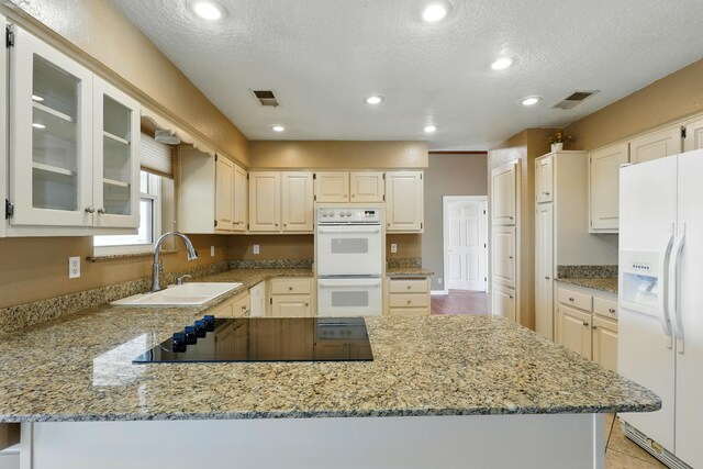 1551 Valley View Dr SW, Los Lunas, NM 87031 - kitchen with white dishwasher, a ceiling fan, a sink, black electric stovetop, and a peninsula