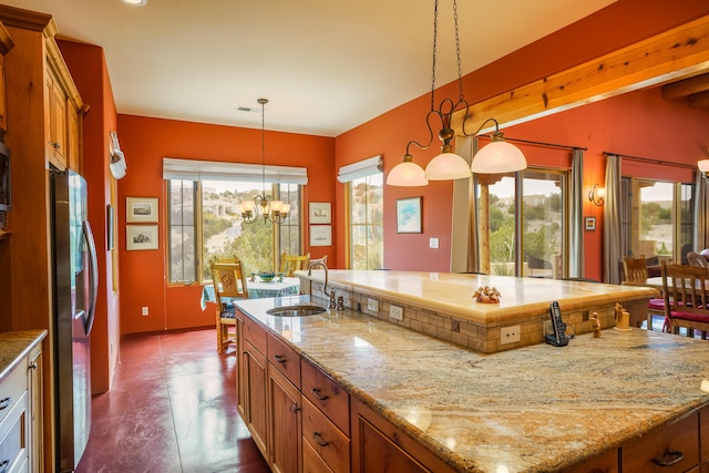 25 Camino Manzano, Placitas, NM 87043 - kitchen with a large island, brown cabinets, appliances with stainless steel finishes, hanging light fixtures, and light stone countertops