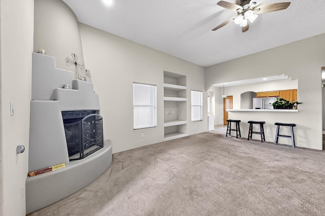 7623 Vista Alta Rd NW, Albuquerque, NM 87114 - living room featuring built in shelves, a ceiling fan, and carpet floors
