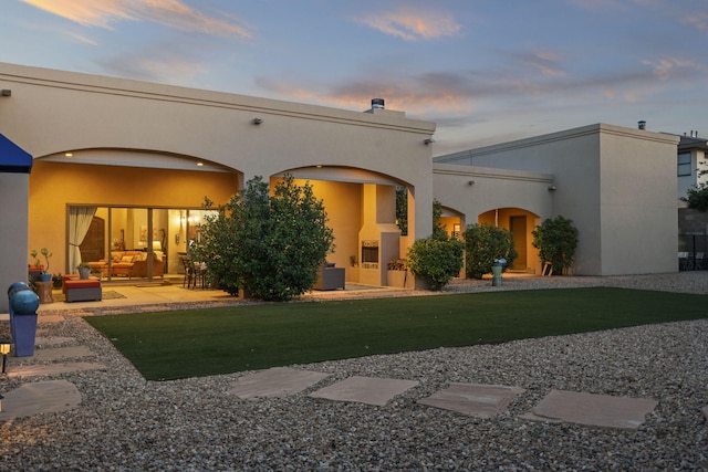 2633 Globe Ct NE, Rio Rancho, NM 87124 - back of house at dusk with an outdoor living space, stucco siding, and a yard