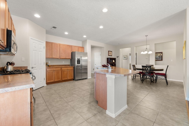 429 Paseo Vista Loop NE, Rio Rancho, NM 87124 - kitchen featuring stainless steel appliances, a textured ceiling, light tile patterned floors, an island with sink, and light countertops