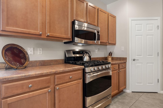 429 Paseo Vista Loop NE, Rio Rancho, NM 87124 - kitchen with stainless steel appliances, light tile patterned flooring, and brown cabinetry