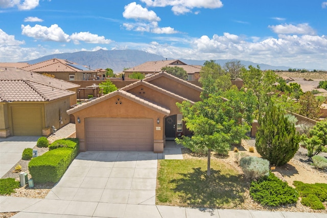 429 Paseo Vista Loop NE, Rio Rancho, NM 87124 - view of front of property featuring a garage, a mountain view, concrete driveway, stucco siding, and a tiled roof