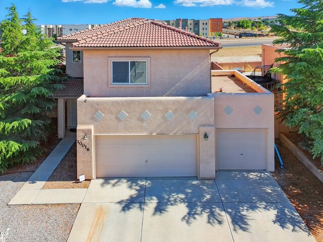 10016 Rio Canon Ave SW, Albuquerque, NM 87121 - mediterranean / spanish-style home with stucco siding, driveway, a tiled roof, and a garage