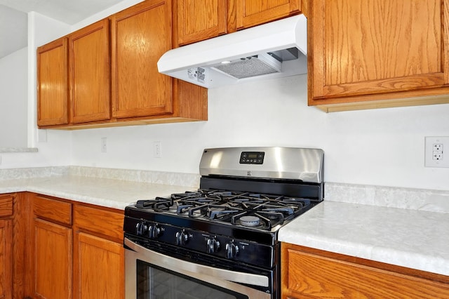 5940 Night Rose Ave NW, Albuquerque, NM 87114 - kitchen with stainless steel range with gas stovetop, under cabinet range hood, light countertops, and brown cabinetry