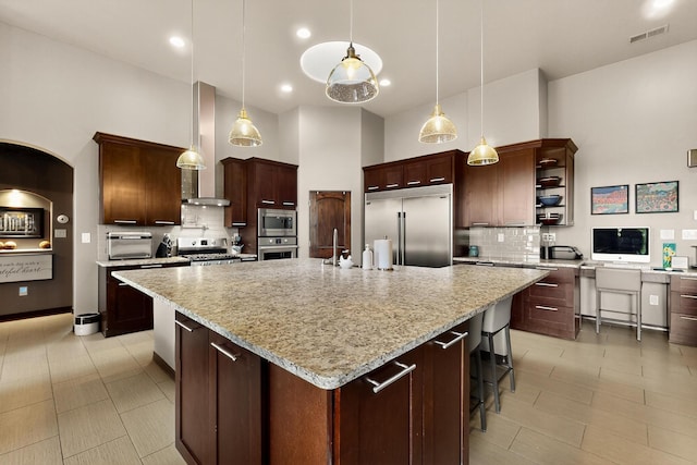 3220 Vatapa Rd NE, Rio Rancho, NM 87144 - kitchen featuring built in appliances, wall chimney exhaust hood, a high ceiling, tasteful backsplash, and a large island with sink