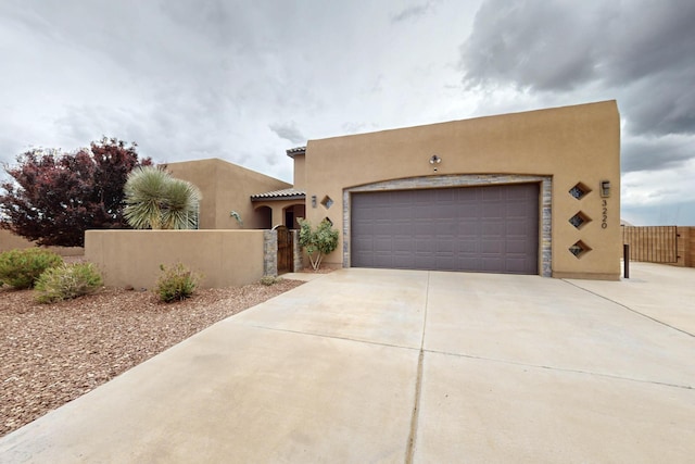 3220 Vatapa Rd NE, Rio Rancho, NM 87144 - adobe home featuring stucco siding, driveway, a garage, and a gate