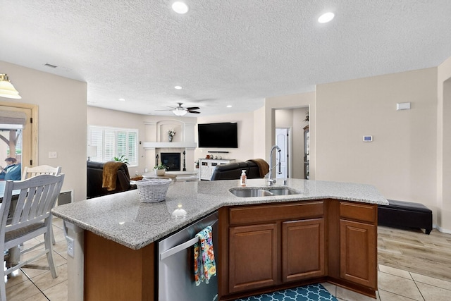 1720 Summer Breeze Dr NW, Albuquerque, NM 87120 - kitchen with stainless steel dishwasher, ceiling fan, light tile patterned flooring, a fireplace with raised hearth, and open floor plan