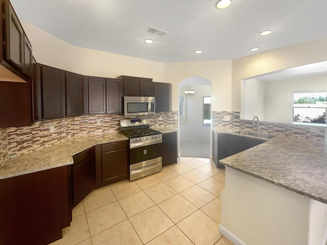 10909 Estribo St NW, Albuquerque, NM 87114 - kitchen featuring stainless steel appliances, a sink, arched walkways, backsplash, and recessed lighting