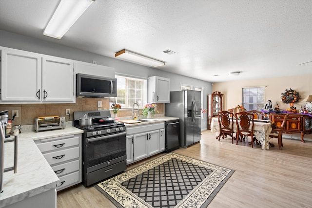 185 La Entrada Rd, Los Lunas, NM 87031 - kitchen with stainless steel appliances, decorative backsplash, light countertops, light wood finished floors, and a textured ceiling