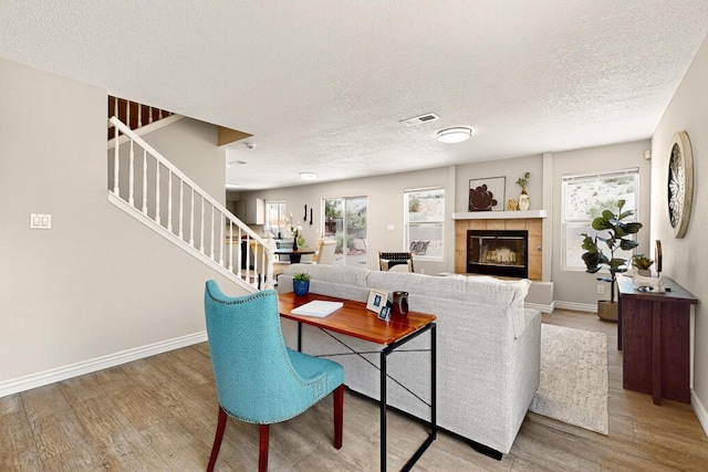 4001 Cresta Park Ave NW, Albuquerque, NM 87114 - living area with wood finished floors, a textured ceiling, stairs, and a tiled fireplace