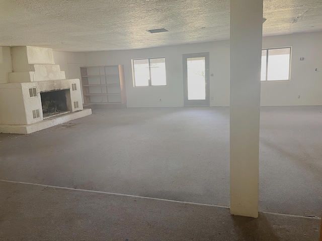 6011 Hubbell Cir SW, Albuquerque, NM 87105 - unfurnished living room featuring healthy amount of natural light, a fireplace, and a textured ceiling