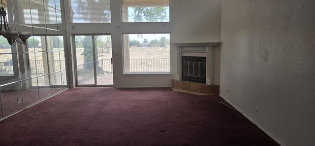 606 Eastlake Ct SE, Rio Rancho, NM 87124 - unfurnished living room featuring carpet floors, healthy amount of natural light, a fireplace, baseboards, and a towering ceiling