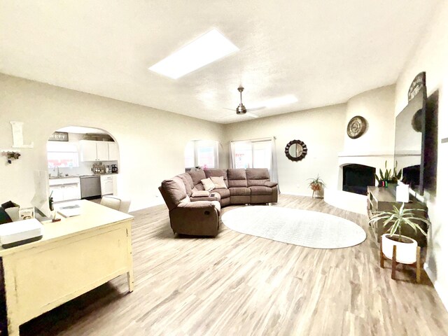 1704 Jack Nicklaus Dr, Rio Communities, NM 87002 - living area featuring wood finished floors, a ceiling fan, plenty of natural light, and a fireplace with raised hearth