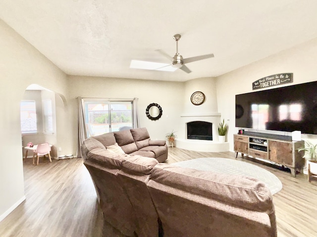 1704 Jack Nicklaus Dr, Rio Communities, NM 87002 - living area featuring ceiling fan, wood finished floors, baseboards, arched walkways, and a fireplace with raised hearth
