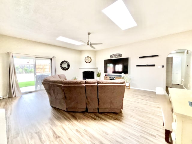 1704 Jack Nicklaus Dr, Rio Communities, NM 87002 - living room featuring light wood finished floors, ceiling fan, arched walkways, and a skylight
