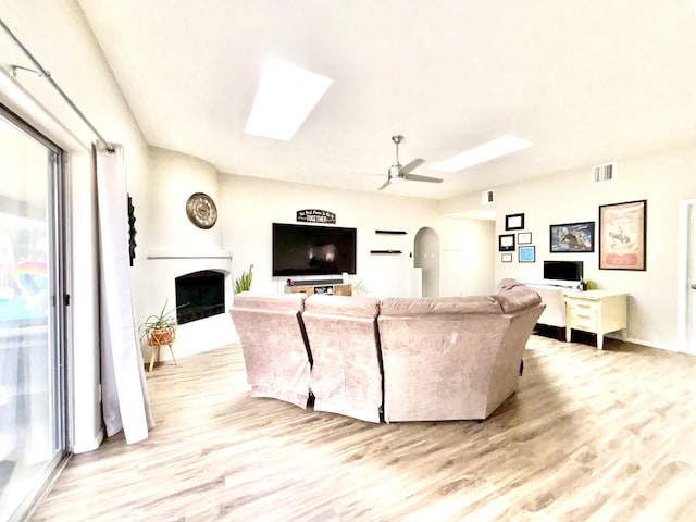 1704 Jack Nicklaus Dr, Rio Communities, NM 87002 - living room with a skylight, light wood-style floors, a fireplace, a ceiling fan, and baseboards