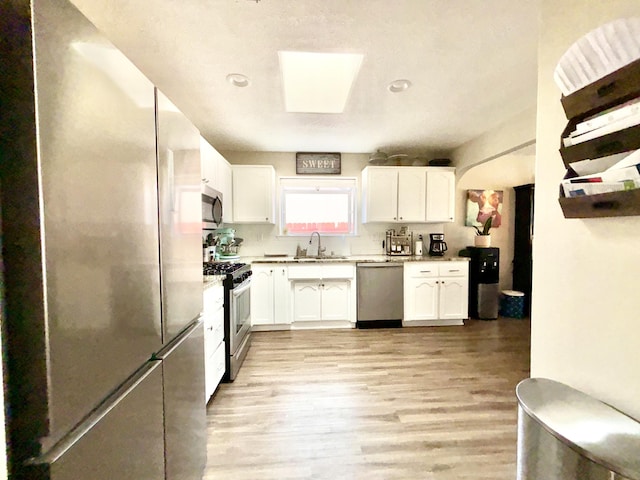 1704 Jack Nicklaus Dr, Rio Communities, NM 87002 - kitchen with stainless steel appliances, a sink, light wood finished floors, white cabinetry, and light countertops
