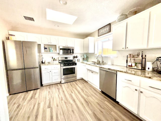 1704 Jack Nicklaus Dr, Rio Communities, NM 87002 - kitchen with appliances with stainless steel finishes, a sink, a skylight, white cabinets, and recessed lighting
