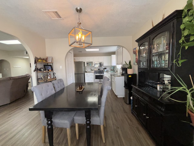 1704 Jack Nicklaus Dr, Rio Communities, NM 87002 - dining area with arched walkways, wood finished floors, a chandelier, and a textured ceiling