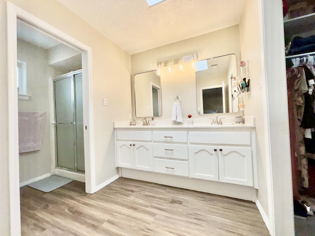 1704 Jack Nicklaus Dr, Rio Communities, NM 87002 - bathroom with wood finished floors, double vanity, a stall shower, and a spacious closet
