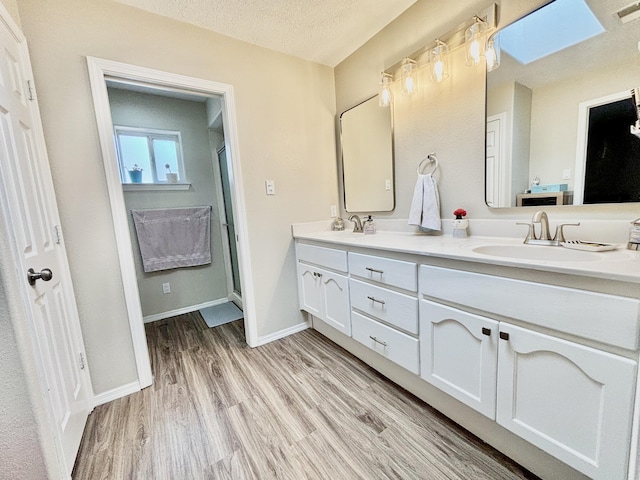 1704 Jack Nicklaus Dr, Rio Communities, NM 87002 - full bath with double vanity, wood finished floors, a shower stall, and a textured ceiling