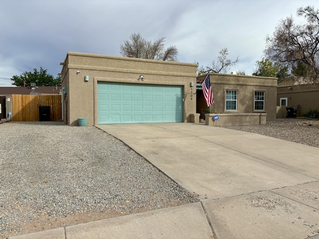 1704 Jack Nicklaus Dr, Rio Communities, NM 87002 - pueblo-style house with concrete driveway, an attached garage, and stucco siding