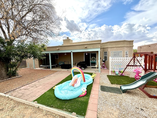 1704 Jack Nicklaus Dr, Rio Communities, NM 87002 - back of property featuring a playground, a patio, a chimney, and stucco siding