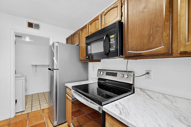 7939 Independence Dr NW, Albuquerque, NM 87120 - kitchen with appliances with stainless steel finishes, washing machine and dryer, light countertops, and light tile patterned floors