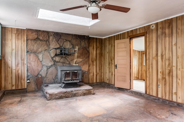 88 Tejano Canyon Rd, Sandia Park, NM 87047 - unfurnished living room with a wood stove, wooden walls, and a ceiling fan