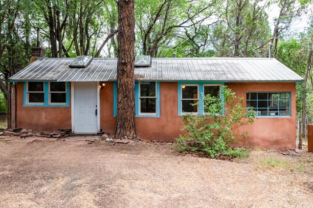 88 Tejano Canyon Rd, Sandia Park, NM 87047 - view of front facade with stucco siding, a chimney, and a metal roof