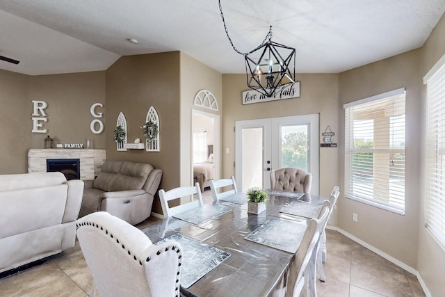 2704 Ghost Ranch St SW, Albuquerque, NM 87121 - dining area featuring a chandelier, french doors, vaulted ceiling, light tile patterned flooring, and a fireplace