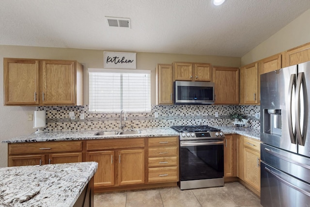2704 Ghost Ranch St SW, Albuquerque, NM 87121 - kitchen featuring stainless steel appliances, decorative backsplash, light stone counters, a textured ceiling, and light tile patterned floors