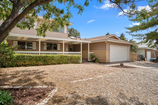 9200 Lagrima De Oro Rd NE, Albuquerque, NM 87111 - view of front facade with brick siding, an attached garage, a porch, and driveway