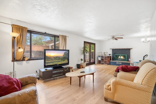 9200 Lagrima De Oro Rd NE, Albuquerque, NM 87111 - living room featuring a ceiling fan, a textured ceiling, healthy amount of natural light, light wood-style flooring, and a fireplace