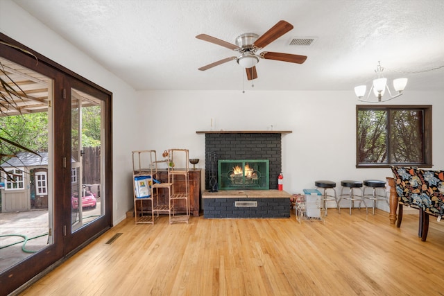 9200 Lagrima De Oro Rd NE, Albuquerque, NM 87111 - living room with hardwood / wood-style flooring, a brick fireplace, a chandelier, ceiling fan, and a textured ceiling